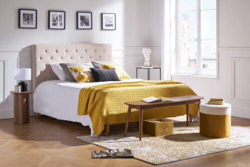 chambre avec tête de lit beige et banc en bois