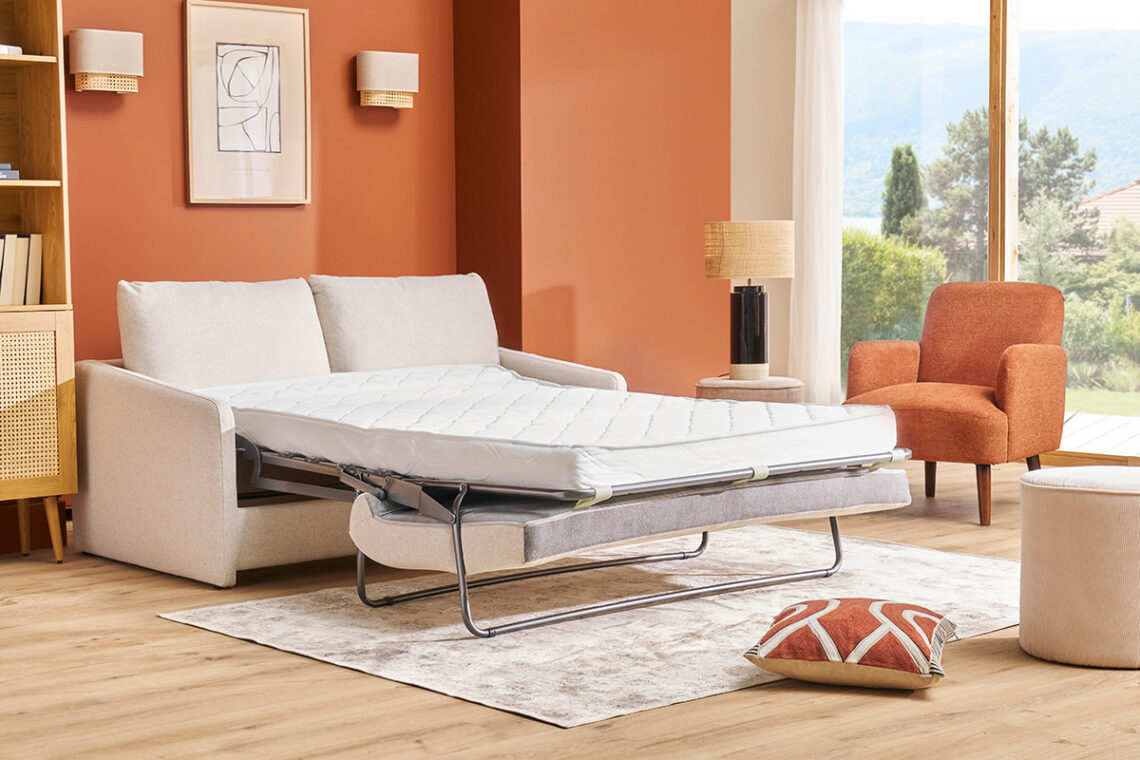 canapé lit ouvert dans salon mur rouge